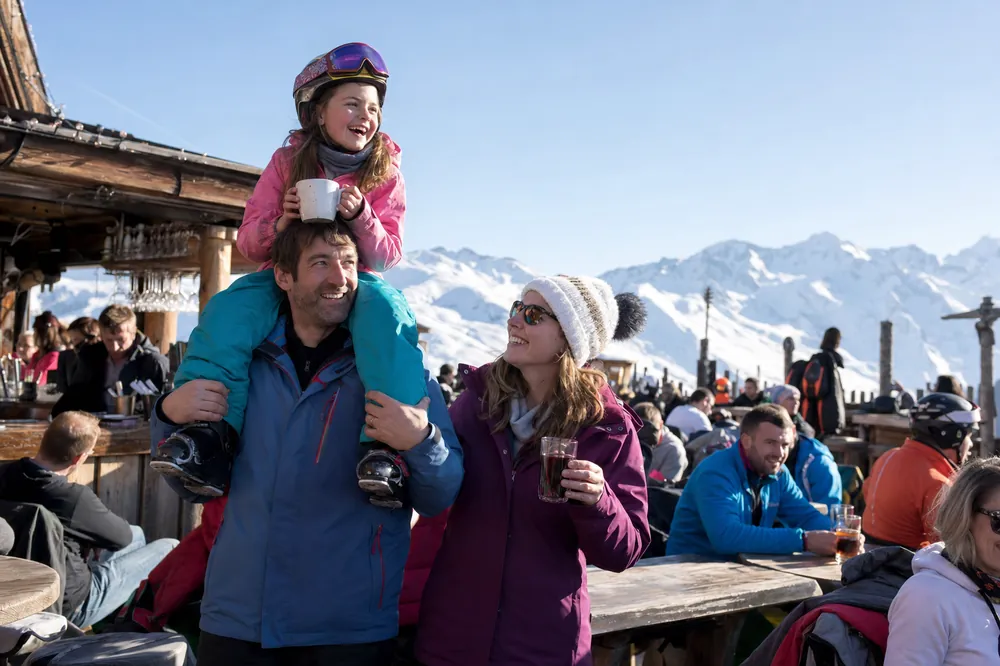 Vader draagt zijn dochter op de schouders op een zonnig terras in de Alpen